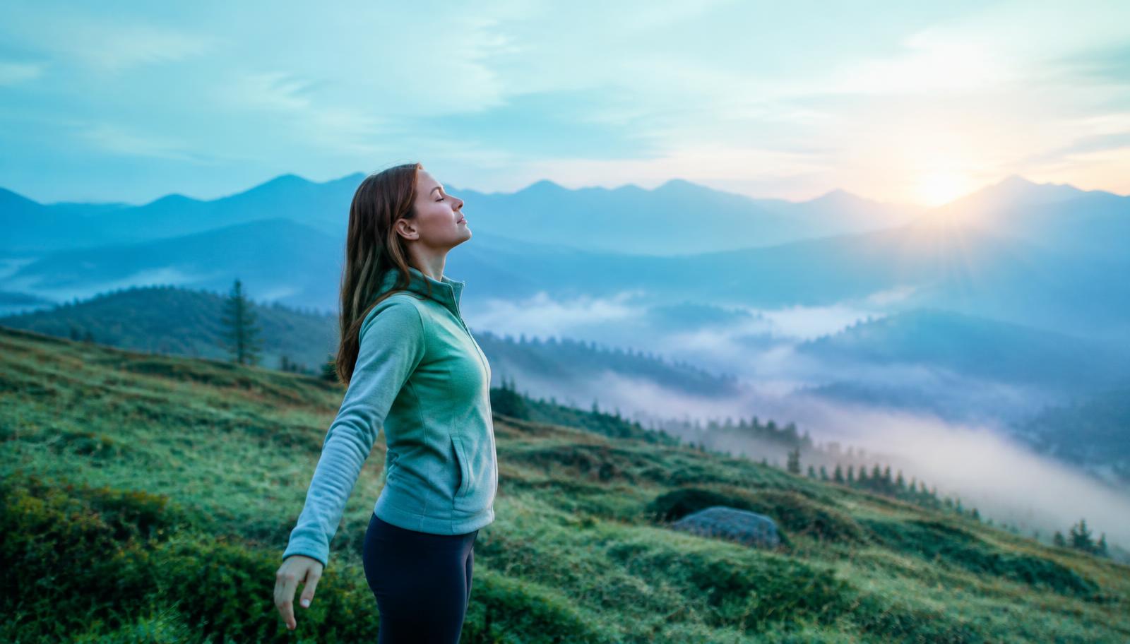 Woman breathing fresh mountain air at sunrise